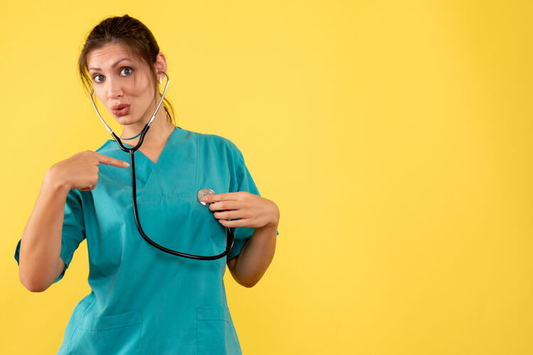 专业正面图黄色背景 穿着医用衬衫 带听诊器的女医生健康黄色护士