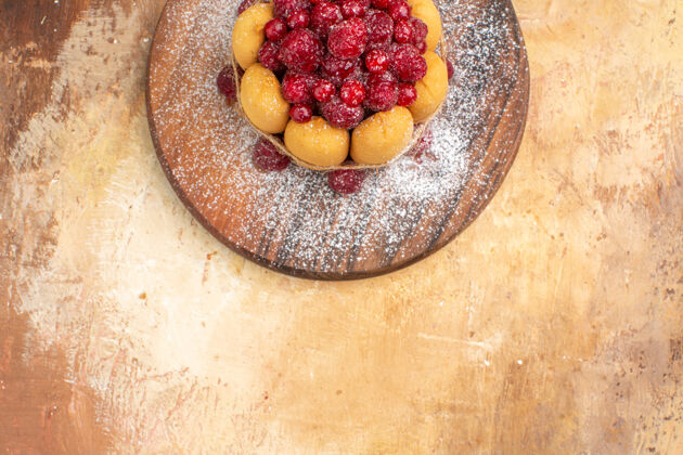 浆果半张自制的水果软蛋糕放在木砧板上 放在五颜六色的桌子上草莓一半农产品