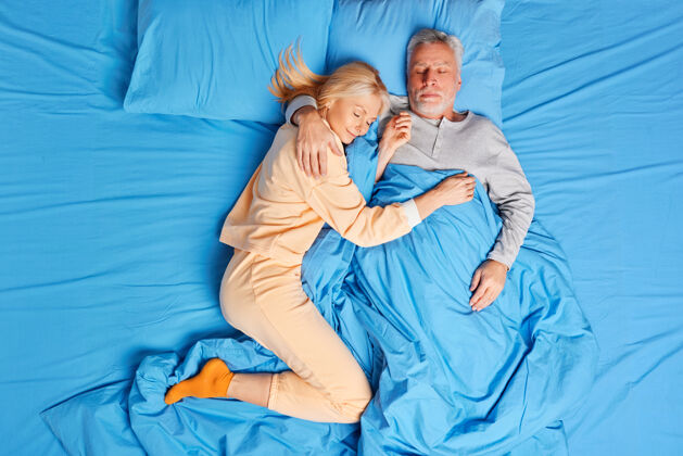 睡眠老年夫妇在床上安详地睡在一起拥抱 在家里有健康的午睡休息睡前家庭和放松的概念枕头周末配偶