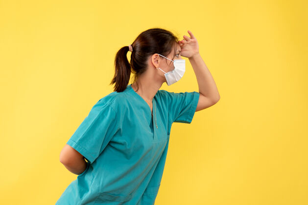 人正面图黄色背景上穿着医用衬衫和无菌口罩的女医生面具站女医生