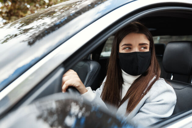 人年轻的女司机坐在车里 戴着口罩开车上班通勤商务女性城市