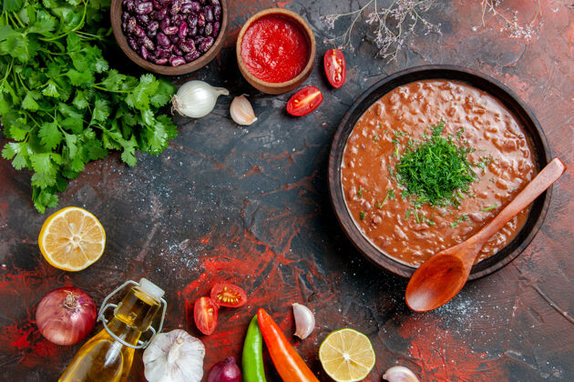 番茄汤番茄汤配一束绿色的油瓶大蒜和勺子放在五颜六色的桌子上串大蒜混合