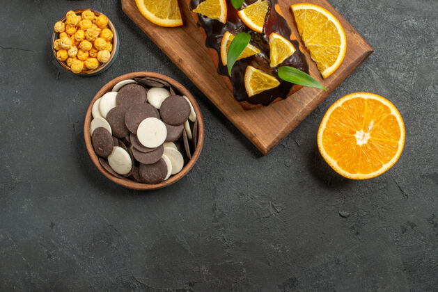 饼干上图：美味的蛋糕切橘子和饼干放在深色桌子的砧板上碗餐厅餐盘