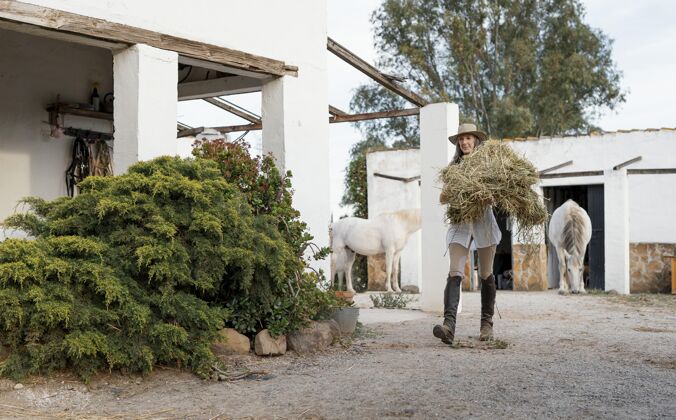 农场女农夫为她的马搬运干草老人乡村农场生活