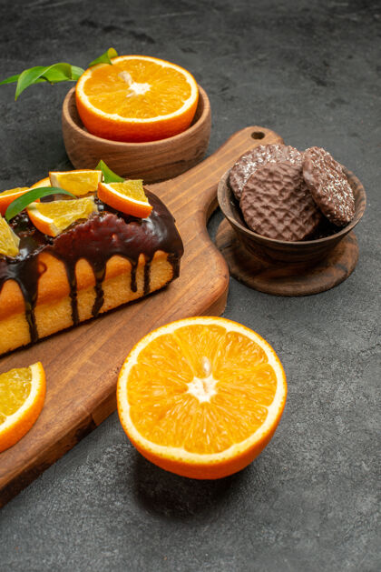 水果特写镜头美味的蛋糕切橘子饼干在砧板上黑暗的桌子上柠檬减肥果汁