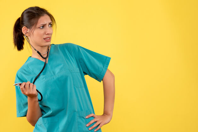 成人正面图黄色背景 穿着医用衬衫 带听诊器的女医生健康肖像人