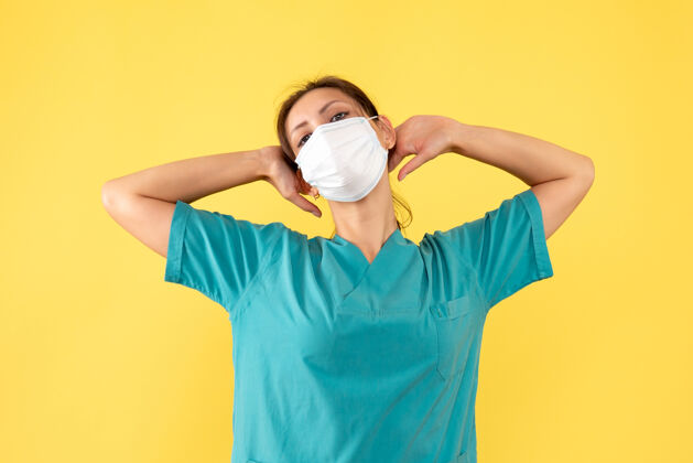 运动装前视图黄色背景上穿着医用衬衫和面罩的女医生女医生一肖像
