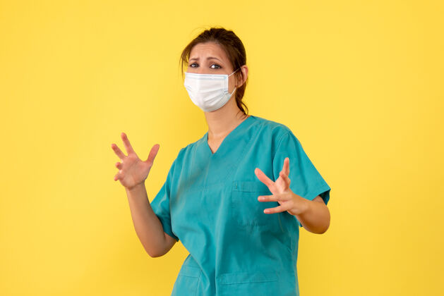 视图前视图黄色背景上穿着医用衬衫和面罩的女医生人自信成人