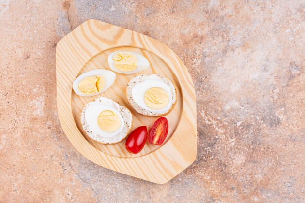 面包房把煮熟的鸡蛋切片 西红柿和面包放在木盘上 放在大理石上谷物外壳面粉