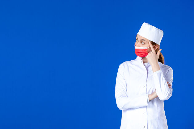 医院正面图：身穿医疗服的年轻护士 蓝色墙上戴着红色防护面具专业人男人
