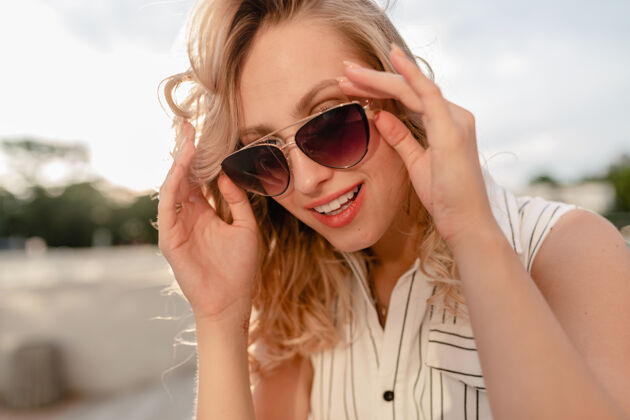 太阳镜城市街道上年轻迷人的时尚金发女郎的特写肖像 穿着夏季时尚的连衣裙 戴着太阳镜年轻牙齿白色