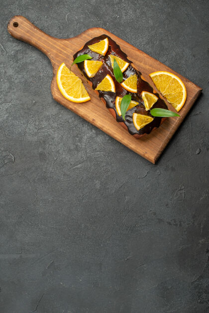 食物上图：美味的蛋糕装饰着橘子和巧克力 放在黑桌子的砧板上板美味蛋糕切