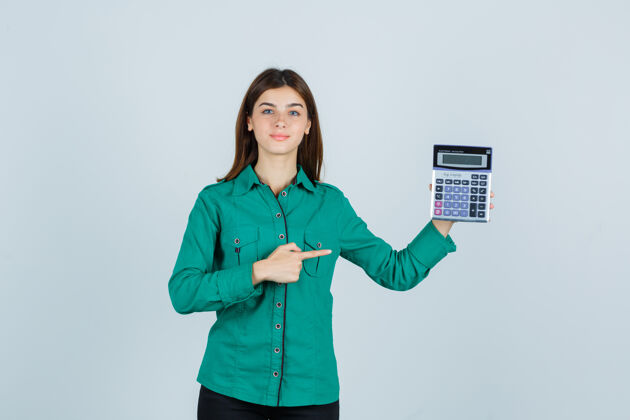 商务穿着绿色衬衫的年轻女士指着计算器 看起来很自信正视图漂亮专业商务女性