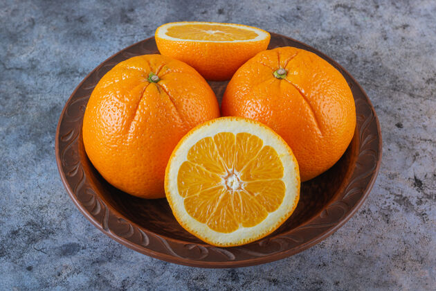 切割有机橙子在灰色盘子上的特写照片水果柑橘叶