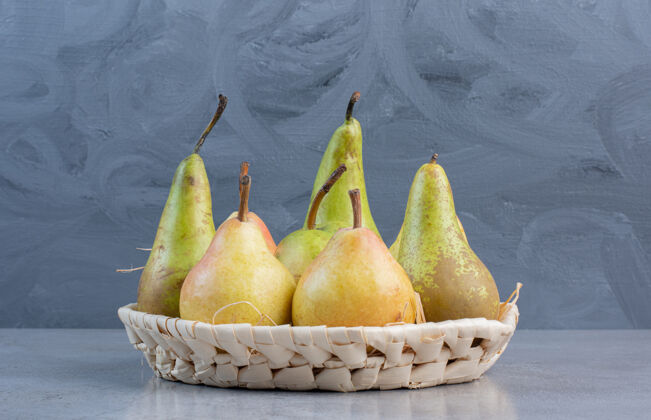 美味一小包各式各样的梨放在大理石背景的白色篮子里篮子梨饮食