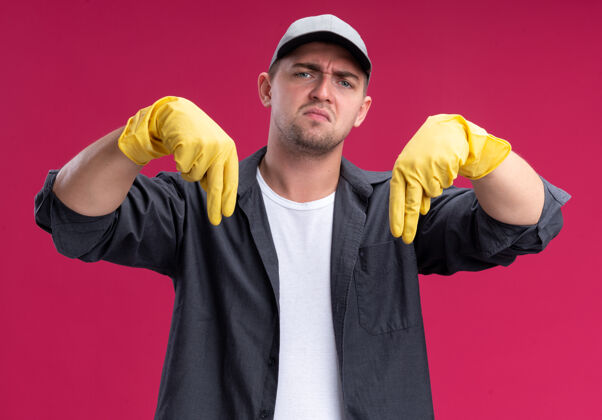 家伙穿着t恤和帽子 戴着手套 站在粉红色的墙上 一个不讨人喜欢的年轻清洁工年轻帽子清洁