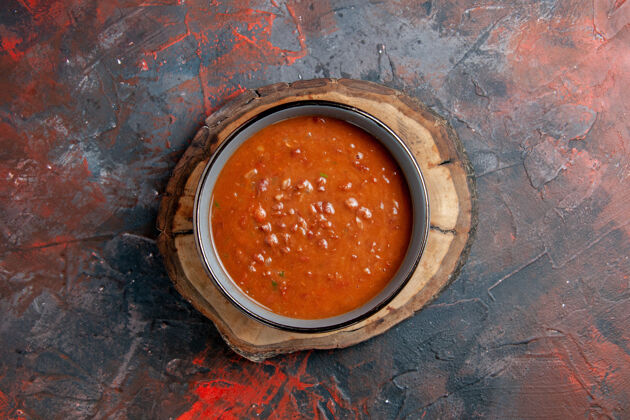 碗杂色桌上棕色木制托盘上蓝色碗里番茄汤的俯视图汤锅番茄汤