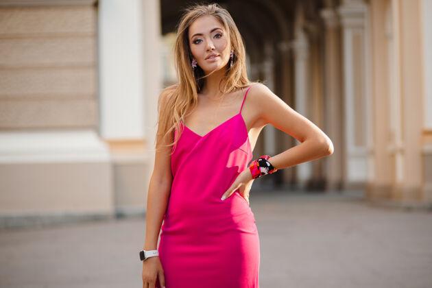 夏天优雅迷人的女人穿着粉色性感夏装 手拿手袋走在街上连衣裙浪漫服装
