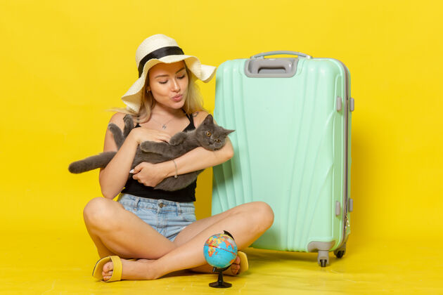 海正面图年轻的女性坐在她的绿色袋子里抱着小猫在黄色的墙上旅行度假旅行海色旅行太阳景色年轻成年人