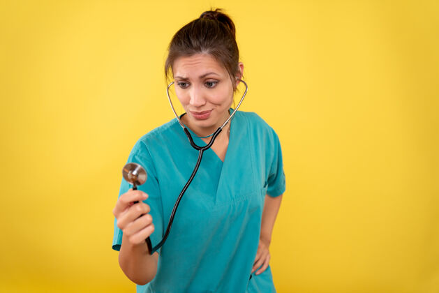 药品正面图黄色背景 穿着医用衬衫 带听诊器的女医生视图医生病毒
