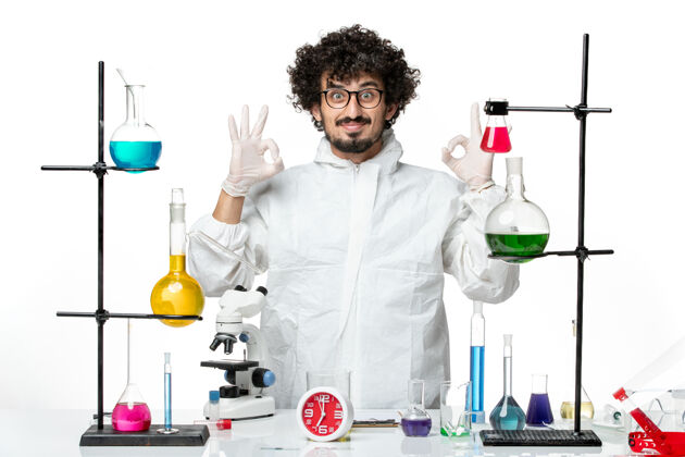实验正面图身着白色特制西服的年轻男科学家站在桌子旁 面带微笑医学视图玻璃