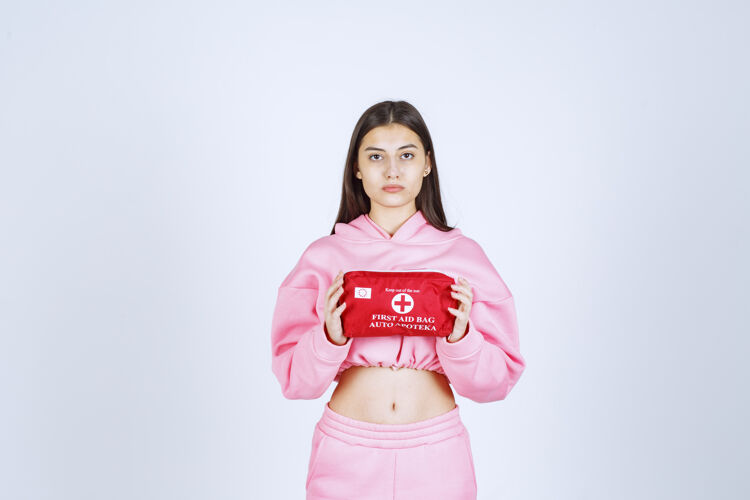 人体模特穿着粉色睡衣的女孩拿着一个红色的急救箱在宣传聪明满意员工