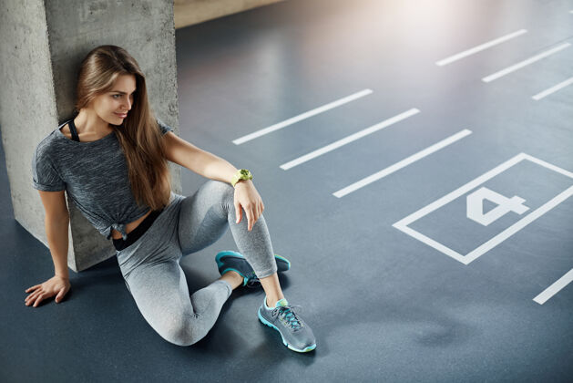 力量健身女教练坐在健身房的地板上计划她的新训练课程强壮的二头肌和三头肌运动员肌肉健康