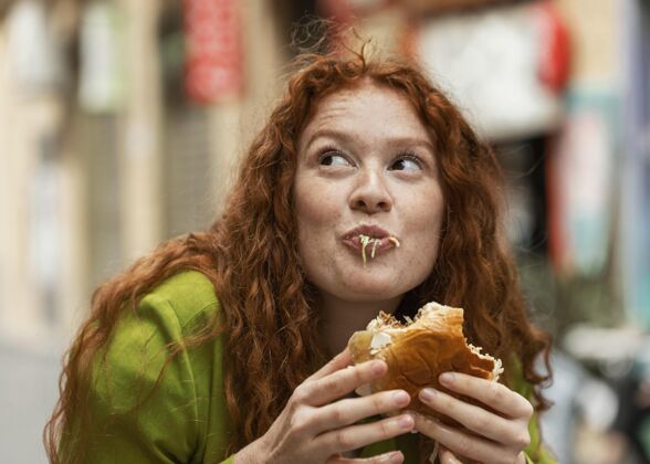 女人美女在户外吃着美味的街边小吃快餐食物都市