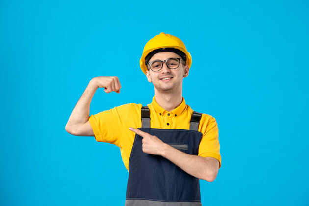 建筑工人穿着黄色制服的男工人在蓝色上弯曲的正面视图头盔制服帽子