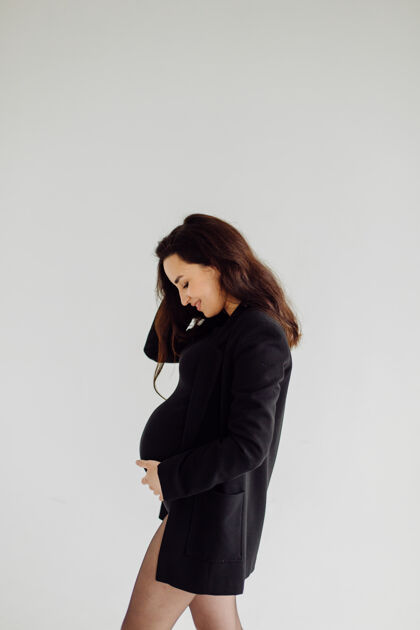 怀孕美丽的年轻孕妇穿着礼服在摄影棚摆姿势腹部腹部母亲