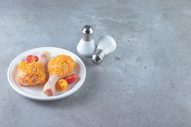美味把生鸡腿放在盐旁边的盘子里 放在大理石背景上准备一餐鸡腿
