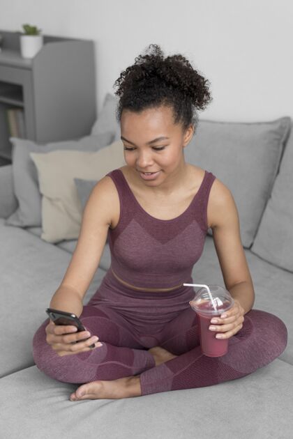 水果健身女士一边用智能手机一边喝排毒果汁食物互联网果汁