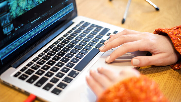 电脑在笔记本电脑上编辑视频的女人桌子上的麦克风在家工作媒体年轻互联网