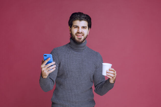 人体模型一个拿着智能手机和咖啡杯的男人看起来很乐观成人年轻人聪明