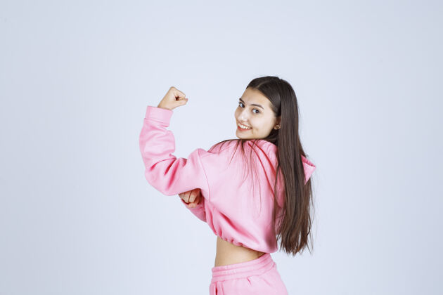 姿势穿着粉色睡衣的女孩展示她的拳头 感觉很强大工人女性人类