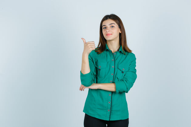 华丽身着绿色衬衫的美丽年轻女士竖起大拇指 看上去自信满满 俯瞰前方女性衬衫专业