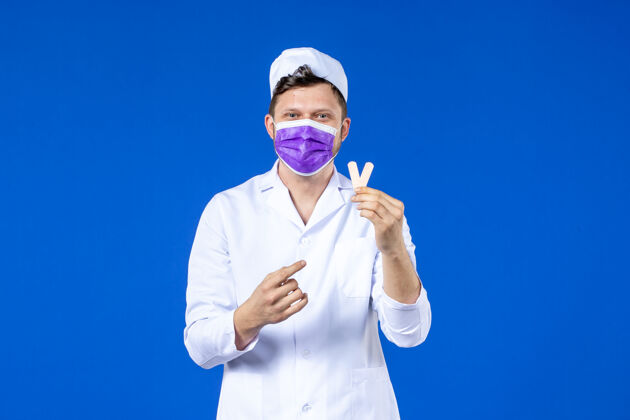贴片前视图中的男医生穿着医疗服和面具举行小医疗补丁蓝色医院外套大流行
