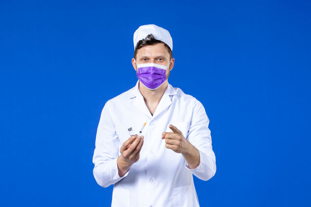 注射男医生的前视图 穿着医疗服 戴着蓝色的注射和疫苗面罩实验服外套工作服
