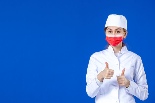服装身穿医疗服的年轻护士的正视图 蓝色的面具上有红色的面具医学年轻护士疾病