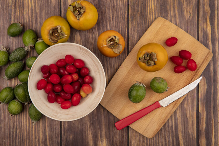 樱桃顶视图新鲜的凤梨樱桃和柿子放在一个木制的菜板上 刀放在木制的表面厨房食物美味