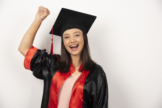年轻在白色背景下庆祝她成功的应届毕业生庆祝帽子微笑