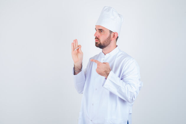 思想年轻的男厨师指着穿着白色制服的香烟 看上去很体贴前视图厨师厨师男人配料