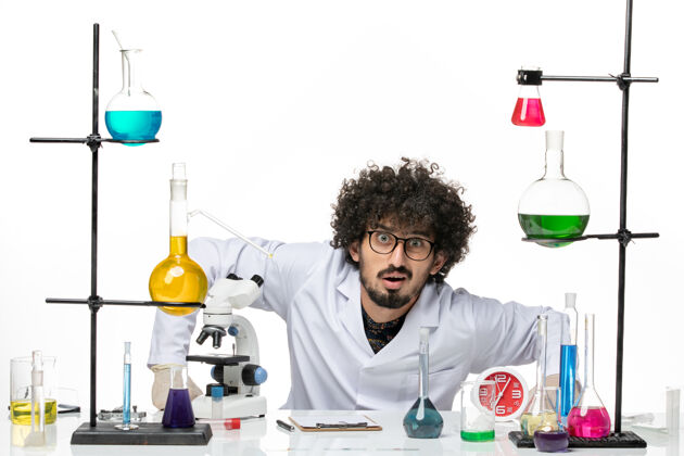 实验室前视图穿着医疗服的男性化学家正坐在桌子前面 在空白处放着溶液男化学家西装医学