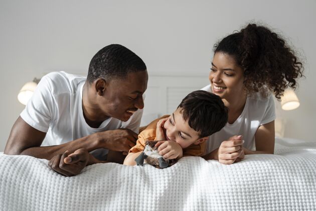 家庭快乐的黑人家庭躺在床上玩得很开心快乐的家庭儿子人
