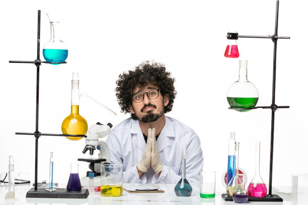 实验室正面图身着医疗服的男性化学家正坐在桌子前 在空白处祈祷解决方案医学祈祷解决方案