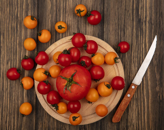 板红色西红柿的顶视图在一个木制的菜板上用刀与樱桃西红柿隔离在一个木制的表面蔬菜樱桃美味