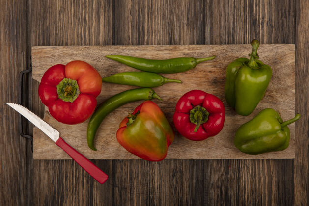 胡椒红椒和青椒的顶视图在木制的厨房板上 刀子放在木制的表面上配料食物营养