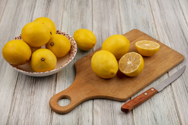 食物一个碗上的酸柠檬的俯视图 柠檬被隔离在木制的厨房板上 刀放在灰色的木制表面上新鲜木材水果