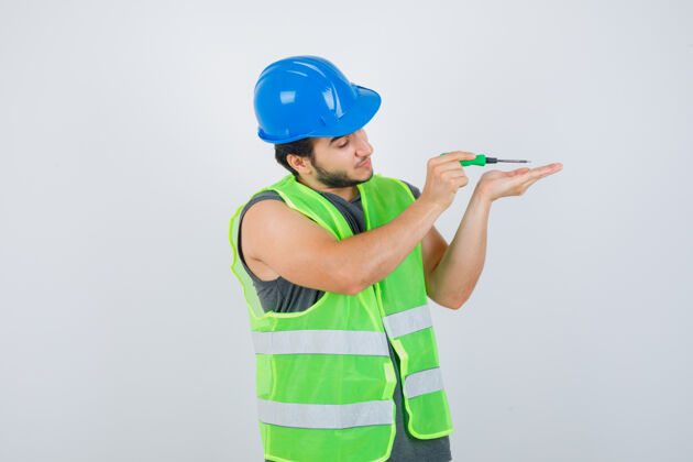 帽子穿着制服的年轻建筑工人一边工作一边用螺丝刀 目光集中 正前方工作协议工具