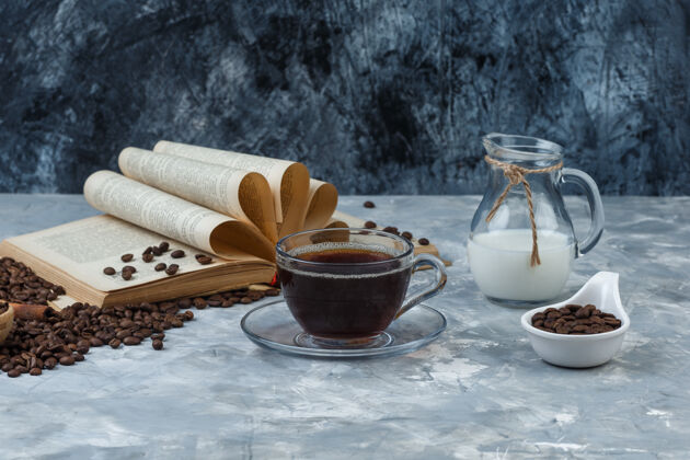 时钟一些咖啡与咖啡豆 书 牛奶在一个杯子上的垃圾和石膏背景 侧视图咖啡馆女性艺术